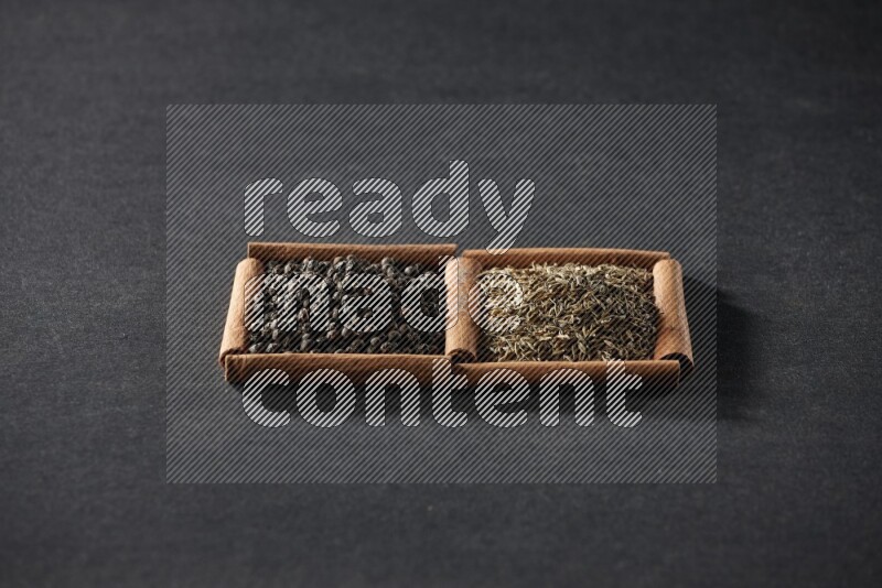 2 squares of cinnamon sticks full of black peppers and cumin on black flooring