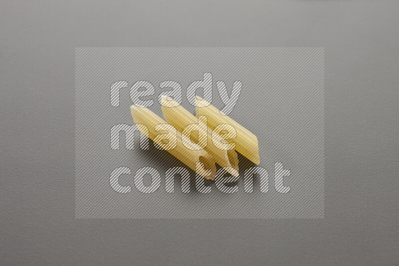 Mini penne pasta on grey background