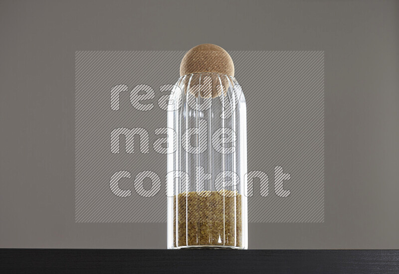 Coarse bulgur in a glass jar on black background