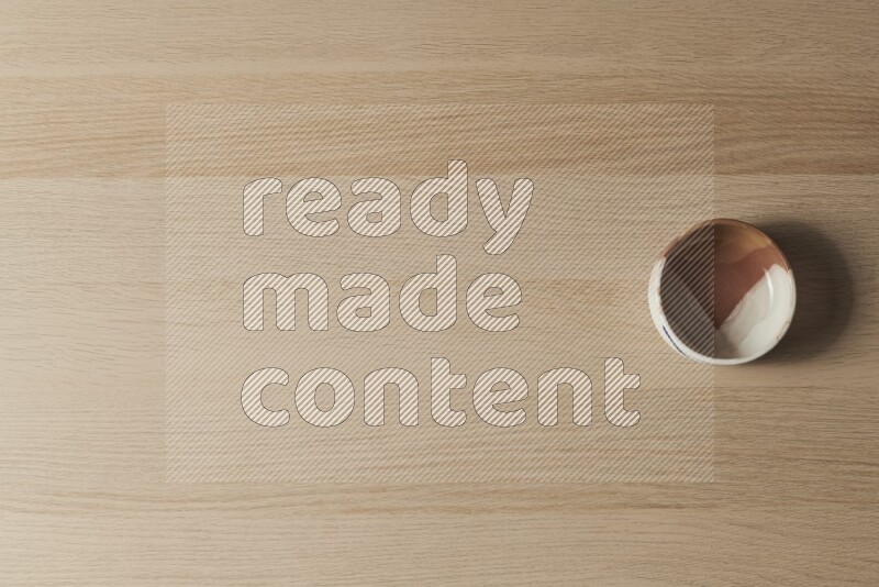 A multicolored pottery bowl on light wooden background