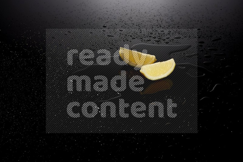 Lemon wedges with water drops, and droplets on black background