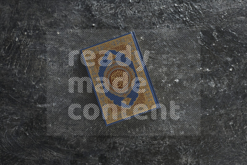 Quran with a prayer beads on textured black background