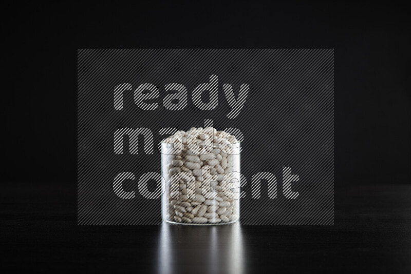 White beans in a glass jar on black background