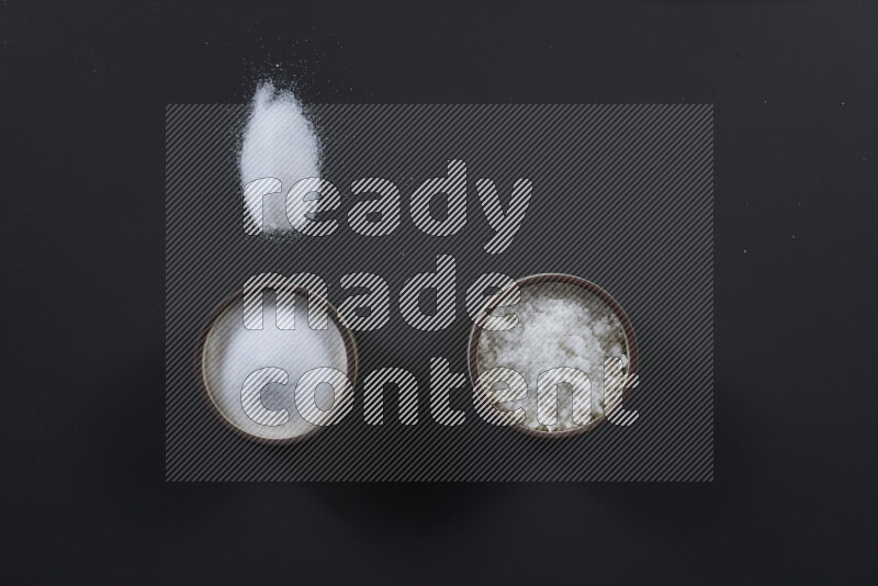 وعاء فخاري ممتلئ بملح الطعام الناعم وملح البحر الخشن على خلفية سوداء