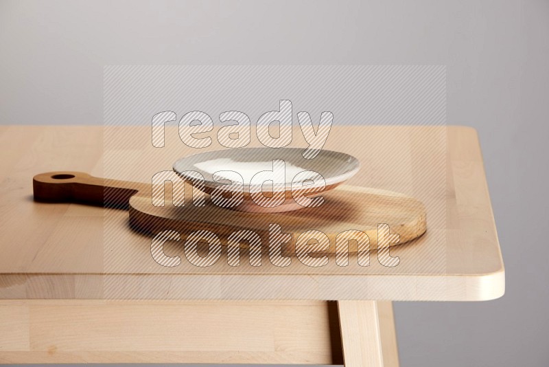 multi colored plate placed on a  wooden oval cutting board on the edge of wooden table