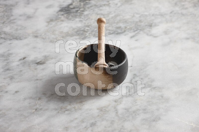 Multicolored pottery bowl with wooden honey dipper in it on grey marble background
