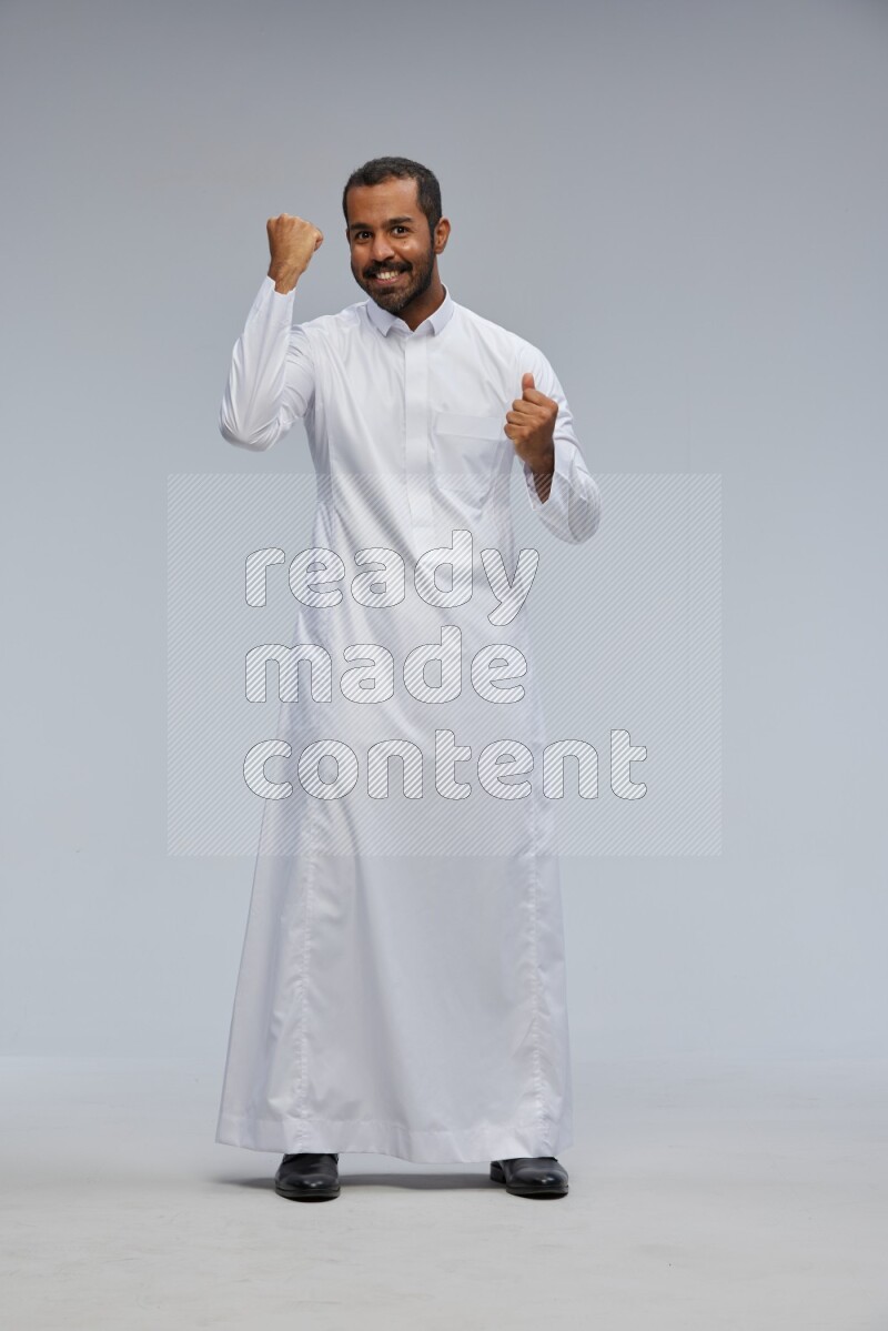 Saudi man Wearing Thob standing interacting with the camera on Gray background