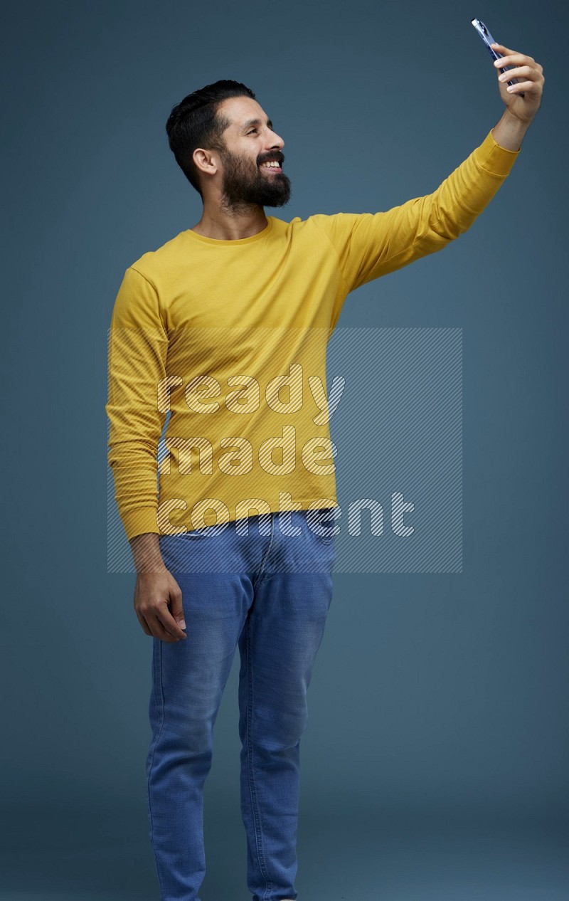 Man Taking a Selfie  in a blue background wearing a yellow shirt