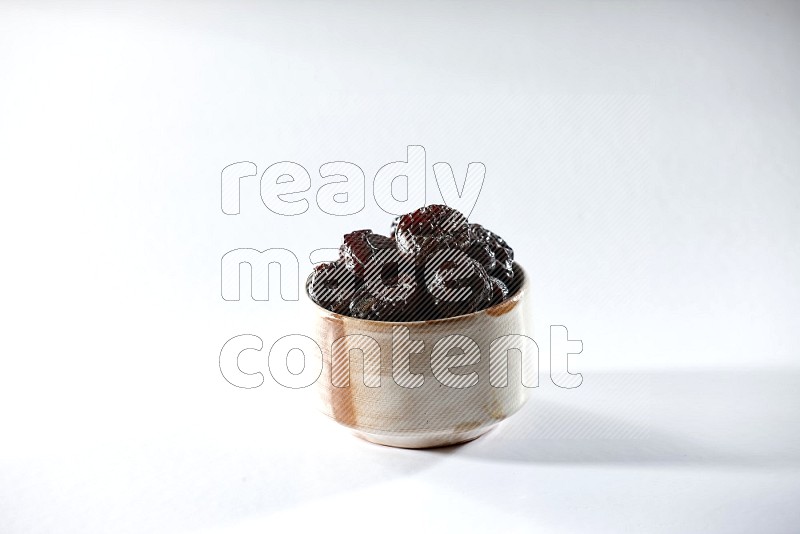 A beige ceramic bowl full of dried plums on a white background in different angles