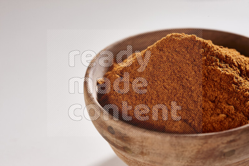 A wooden bowl full of ground paprika powder on white background
