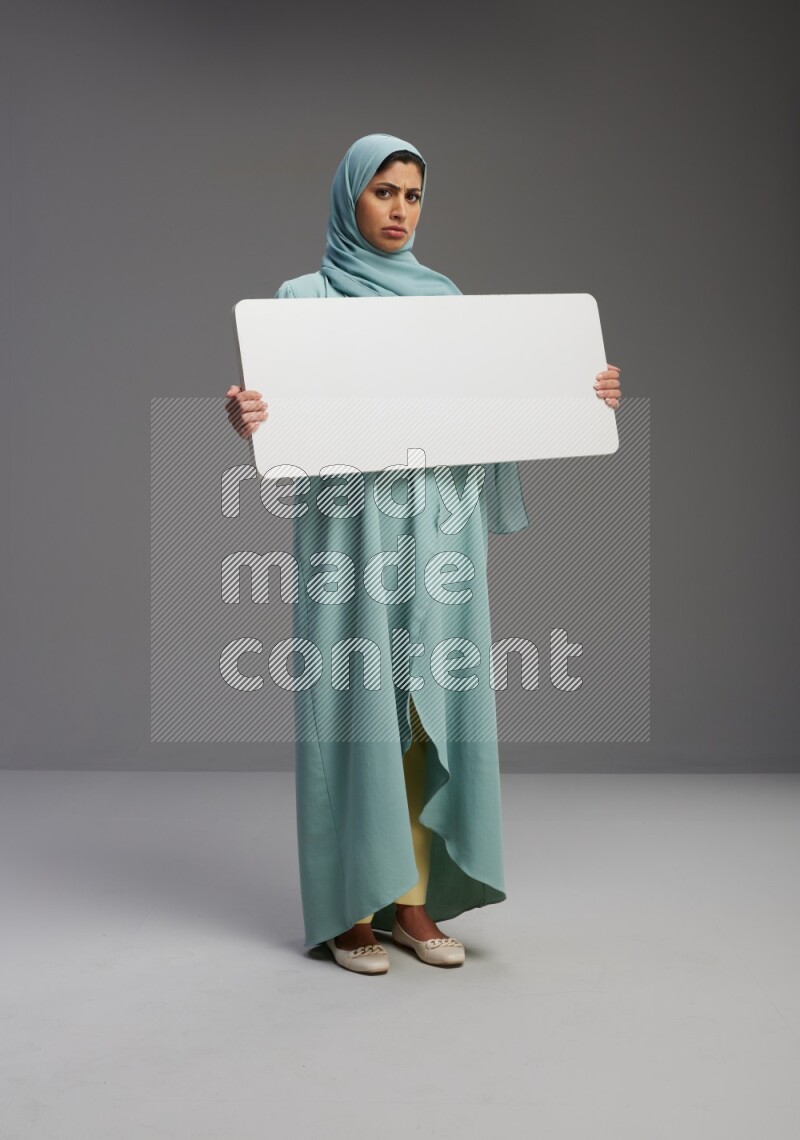 Saudi Woman wearing Abaya standing holding board on Gray background