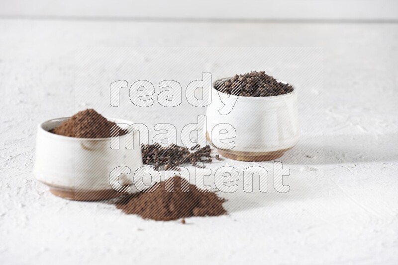 وعاءين من السيراميك بيج اللون، أحدهما مملوء بالقرنفل والآخر مملوء بالبودرة على أرضية بيضاء