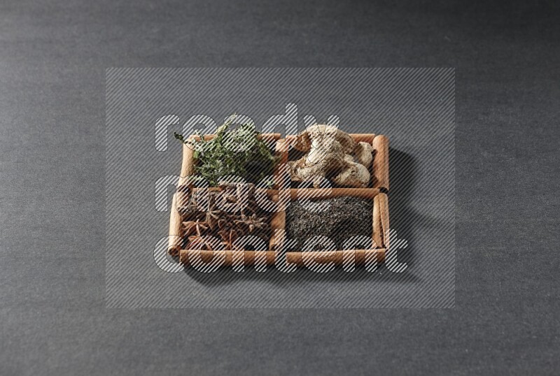 4 squares of cinnamon sticks full of black tea, dried ginger, dried mint leaves and star anise on black flooring