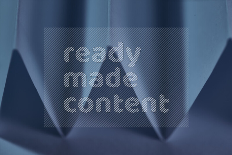 صورة مجردة مقربة تظهر طيات ورقية هندسية حادة بتدرجات اللون الأزرق