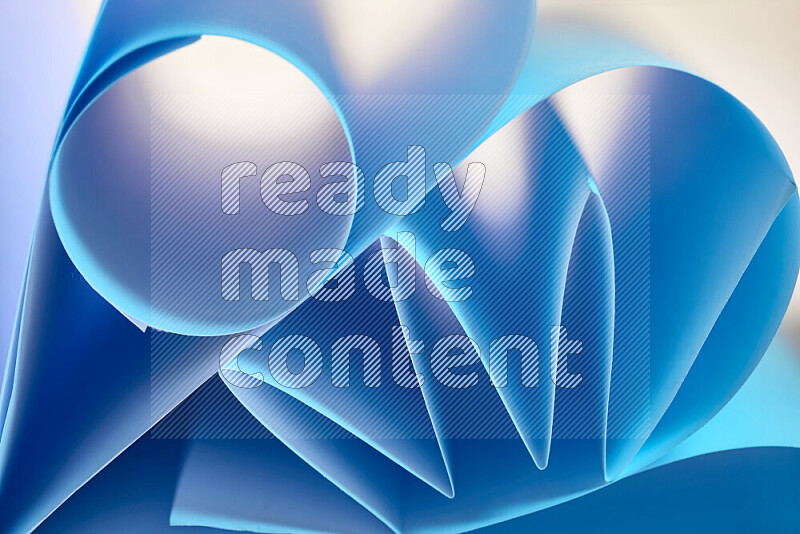 An artistic display of paper folds creating a harmonious blend of geometric shapes, highlighted by soft lighting in blue tones