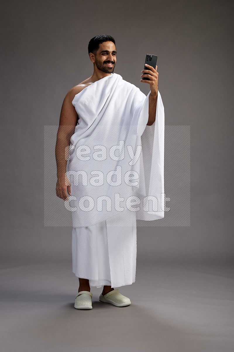 A man wearing Ehram Standing taking selfie on gray background