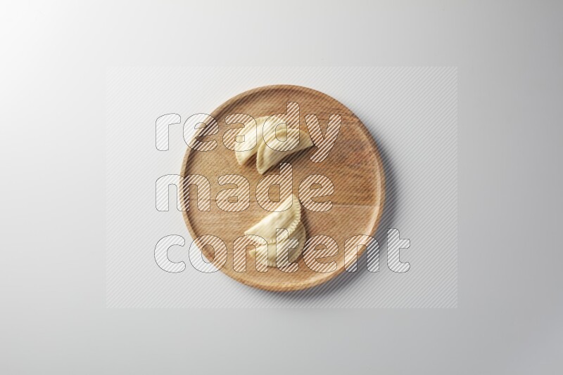 Four Sambosas on a wooden round plate on a white background