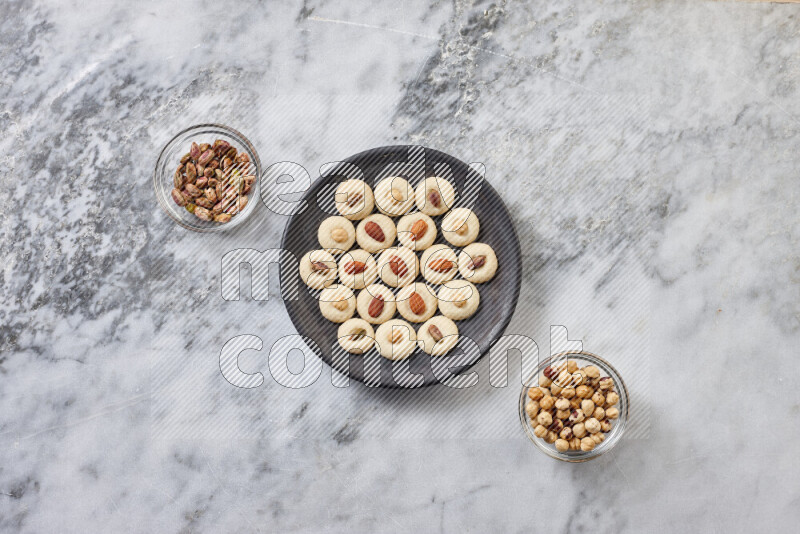 Ghoriba step by step with its ingredient, flour, powdered sugar, ghee and nuts on grey marble background