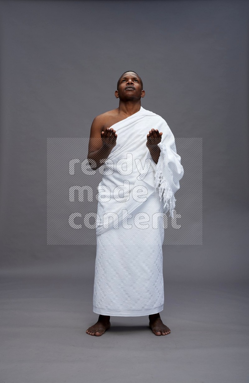 A man wearing Ehram Standing dua'a on gray background