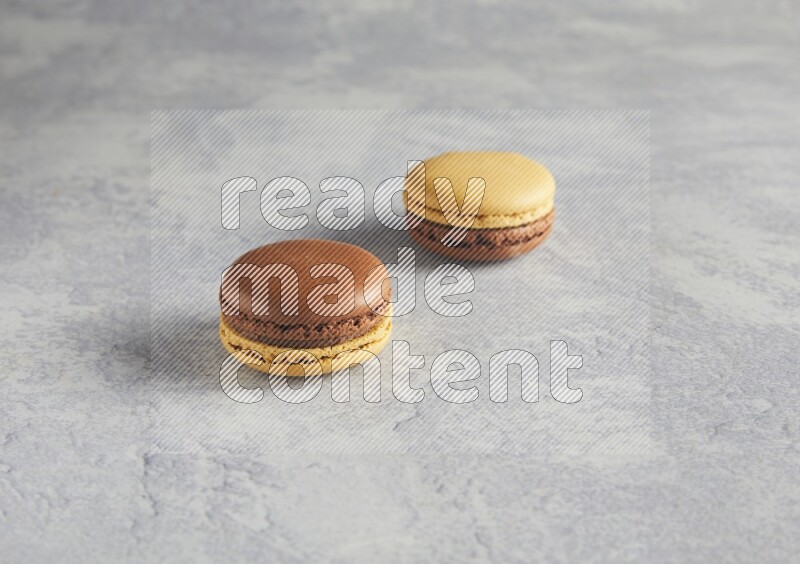 45º Shot of two Yellow and Brown Chai Latte macarons r on white  marble background