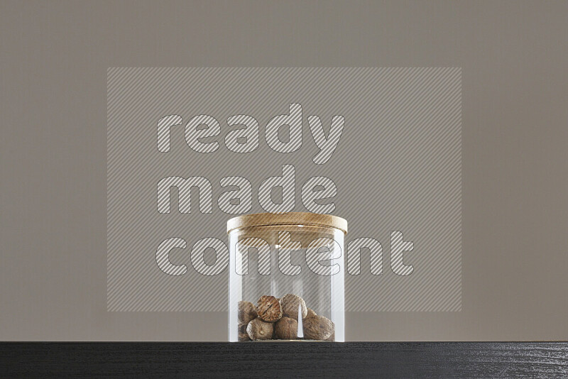 Nutmeg in a glass jar on black background