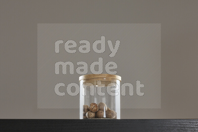 جوزة الطيب في وعاء زجاجي على خلفية سوداء