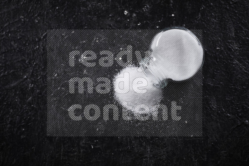 وعاء زجاجي ممتلئ بالملح الأبيض الناعم على خلفية سوداء