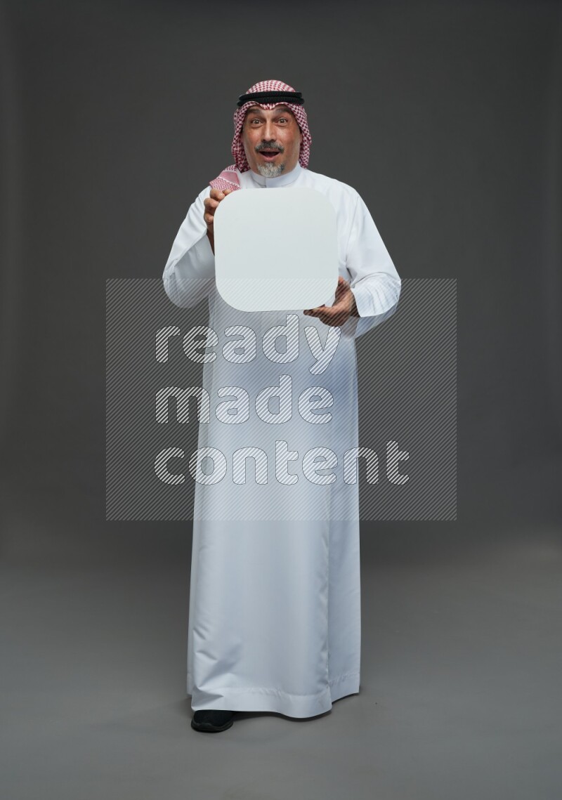 Saudi man with shomag Standing holding social media sing on gray background