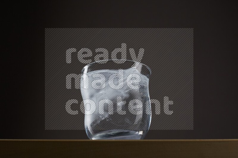 Low angle shot of a glass of water and ice on grey background