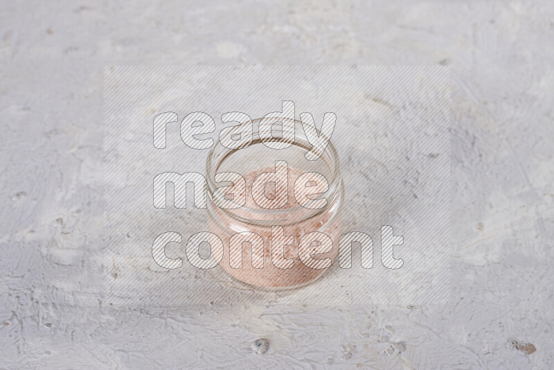 A glass jar full of fine himalayan salt on white background