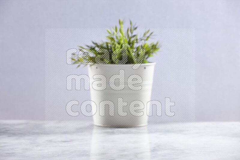 Artificial plant in white pot on grey marble background