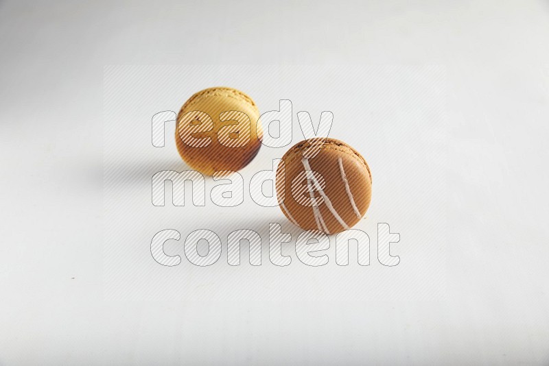 45º Shot of of two assorted Brown Irish Cream, and Yellow Crème Brulée macarons on white background