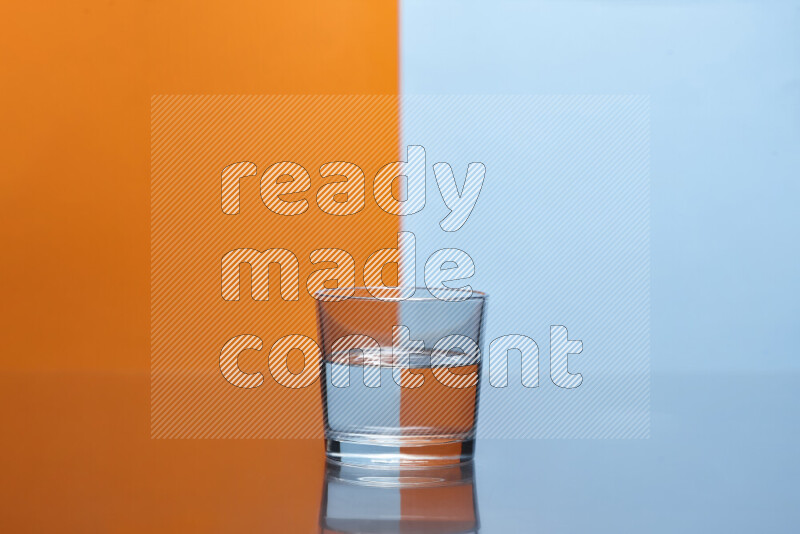 تظهر الصورة أواني زجاجية ممتلئة بالماء موضوعة على خلفية من اللونين البرتقالي والأزرق الفاتح