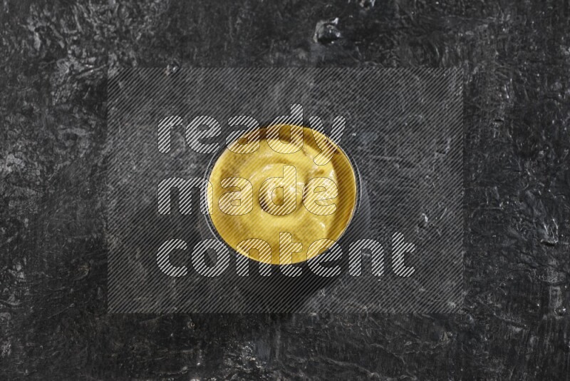 وعاء فخاري أسود ممتلئ بمعجون الخردل علي خلفية سوداء