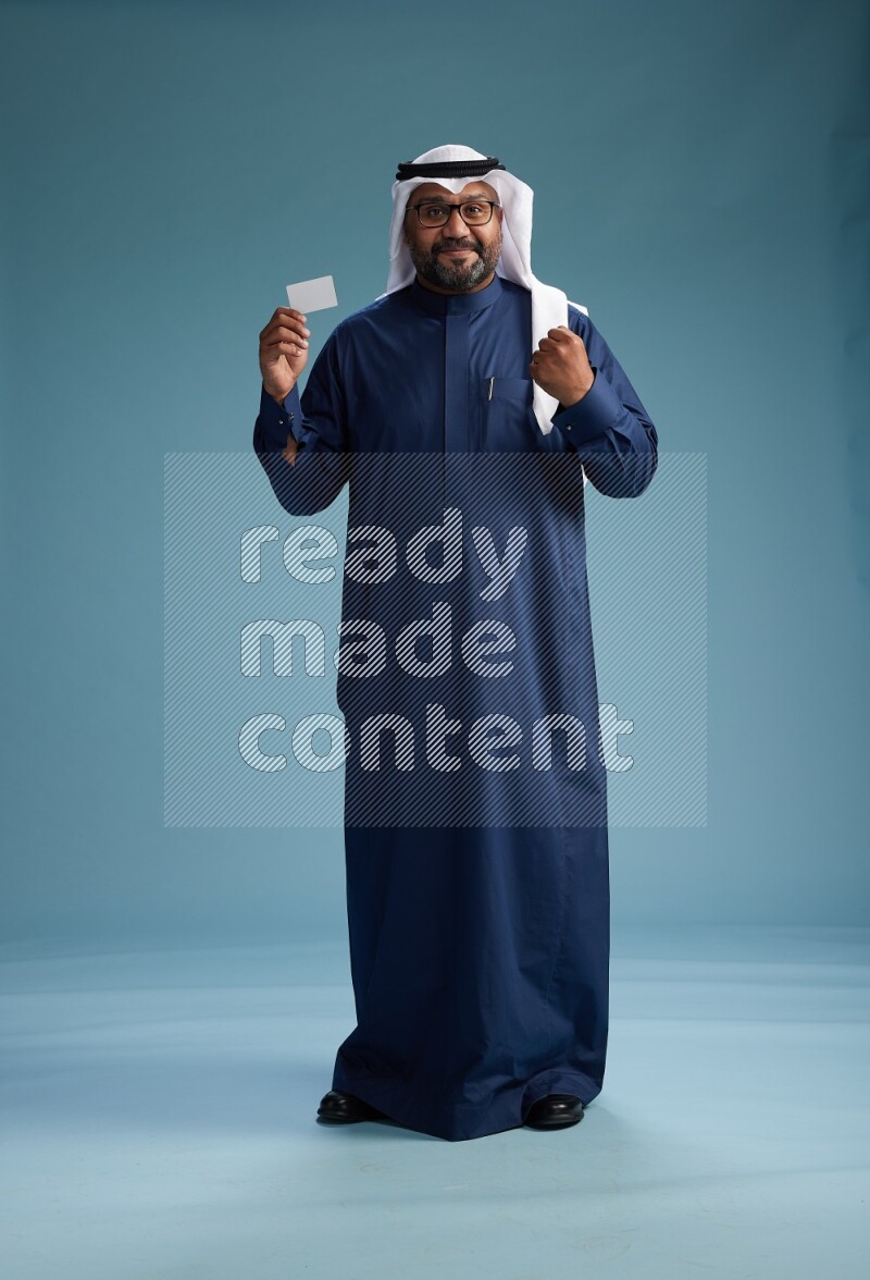 Saudi Man with shimag Standing holding ATM on blue background