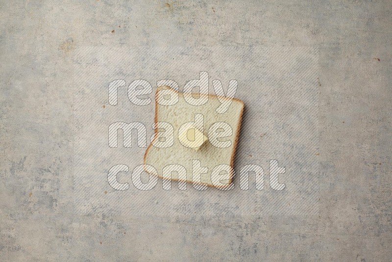 White toast slice with a butter cube on alight blue textured background