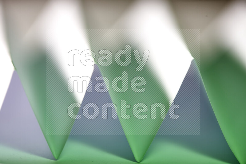 A close-up abstract image showing sharp geometric paper folds in white and green gradients