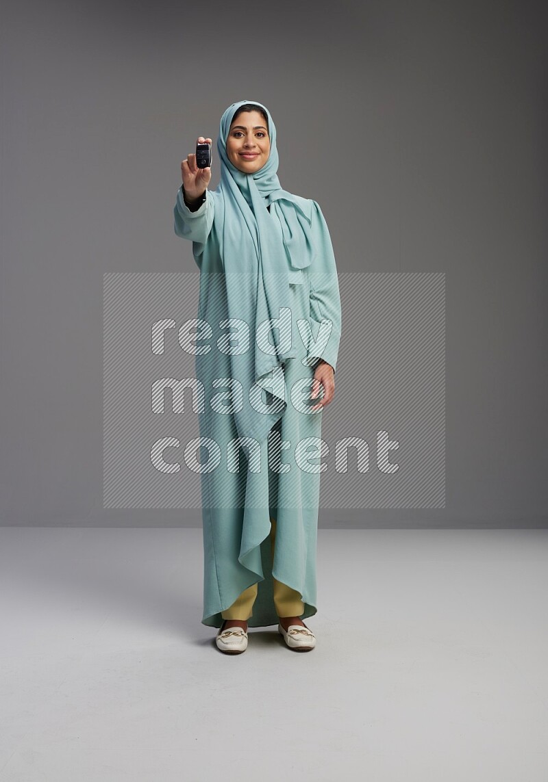 Saudi Woman wearing Abaya standing holding car key on Gray background