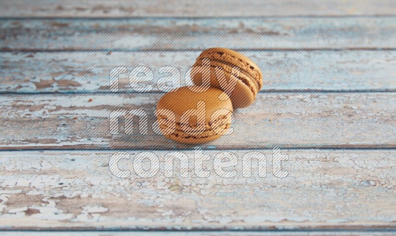 45º Shot of two Brown Maple Taffy macarons on light blue wooden background