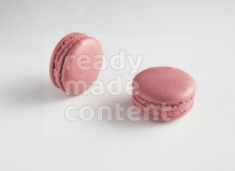 45º Shot of two Pink Raspberry macarons on white background