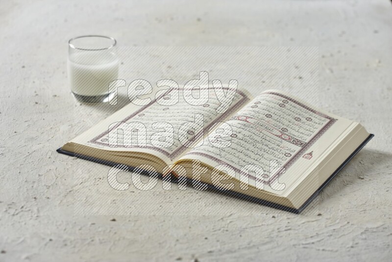 Quran with dates, prayer beads and different drinks all placed on textured white background