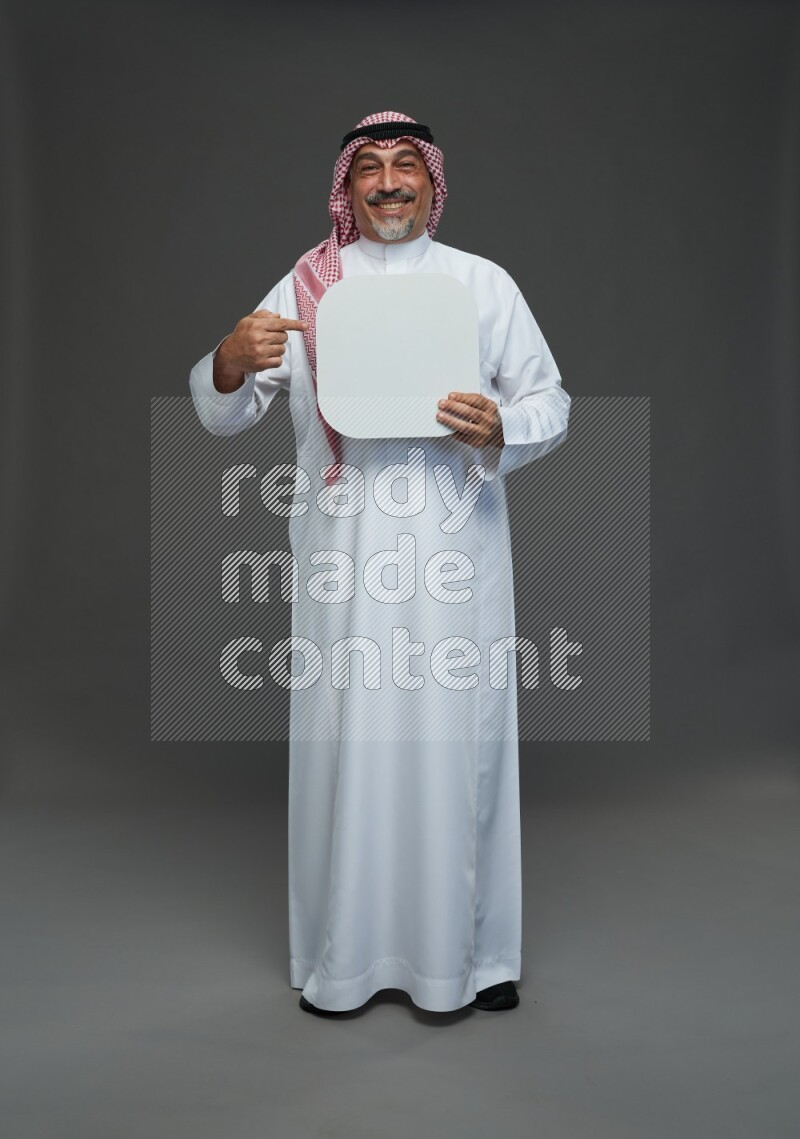 Saudi man with shomag Standing holding social media sing on gray background
