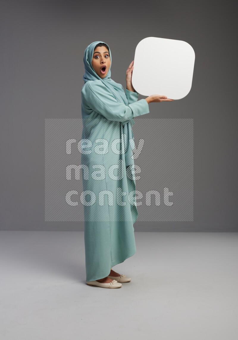Saudi Woman wearing Abaya standing holding social media sign on Gray background