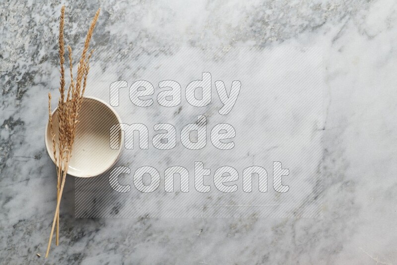 Wheat stalks on beige pottery bowl on grey marble background