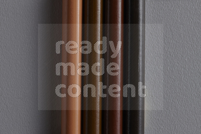 A collection of colored pencils arranged showcasing a gradient of brown hues on grey background