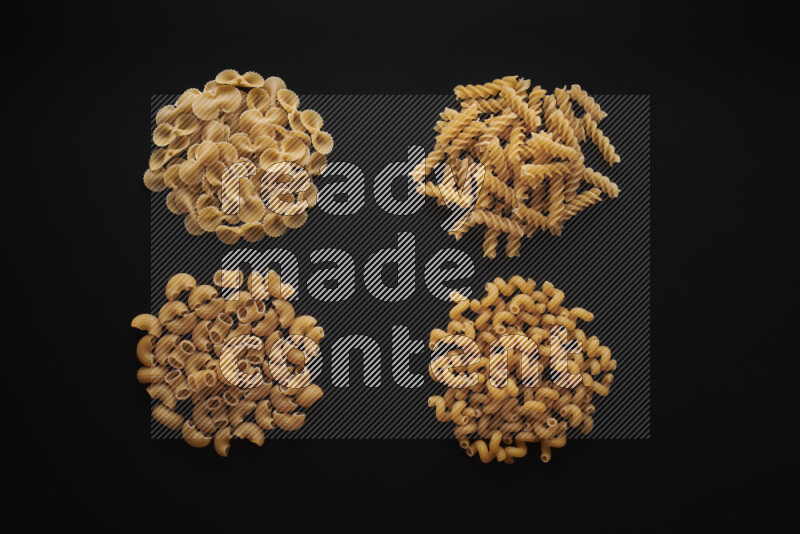 Different pasta types in bunches on black background