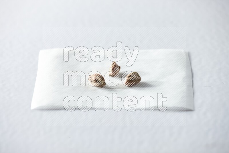 3 peeled pistachios on a piece of paper on a white background in different angles