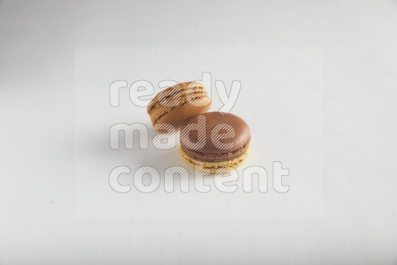 45º Shot of of two assorted Brown Irish Cream, and Yellow, and Brown Chai Latte macarons on white background