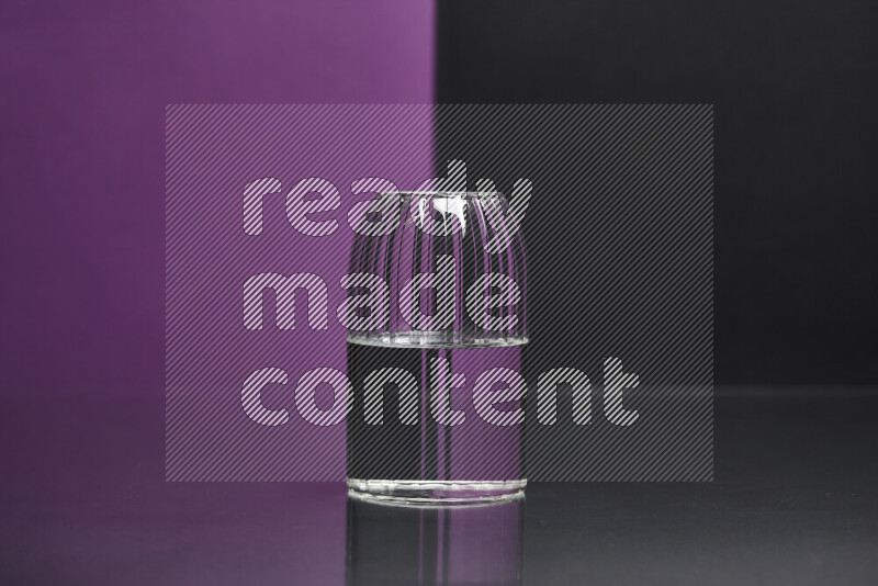 The image features a clear glassware filled with water, set against purple and black background