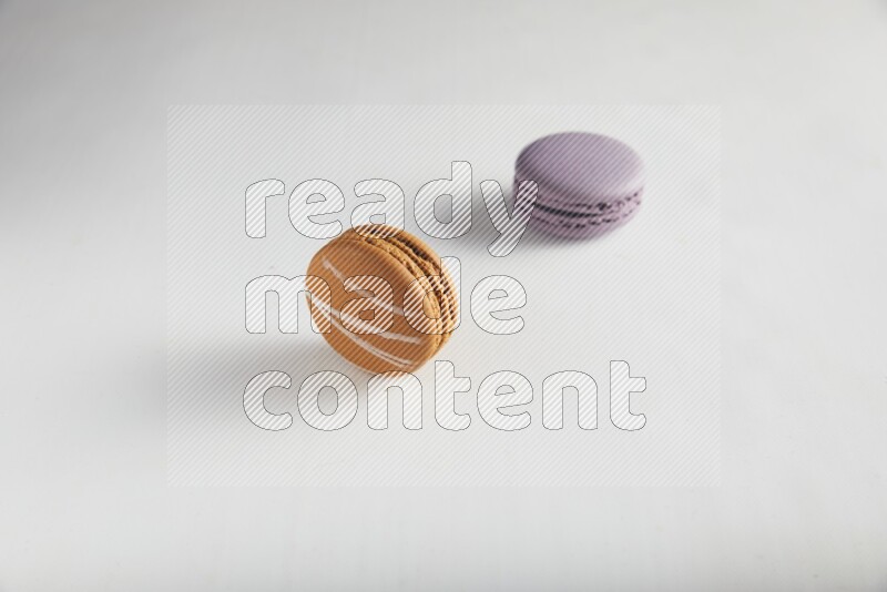 45º Shot of of two assorted Brown Irish Cream, and Purple Blueberry macarons on white background
